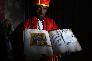 Mönch zeigt eine historische Bibel im Bergkloster bei Lalibela. Äthiopien