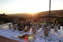 Ant´s Africa Safaris, Weinverkostung auf gedecktem Tisch mit Sonnenuntergang im Hintergrund