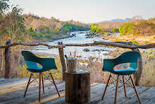 Zwei Stühle auf dem Holzdeck vor dem Flusslauf