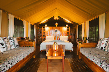Vuma Hills Tented Camp. Blick ins Zelt, Sitzgelegenheit mit Tisch und Doppelbett im Hintergrund. Tansania