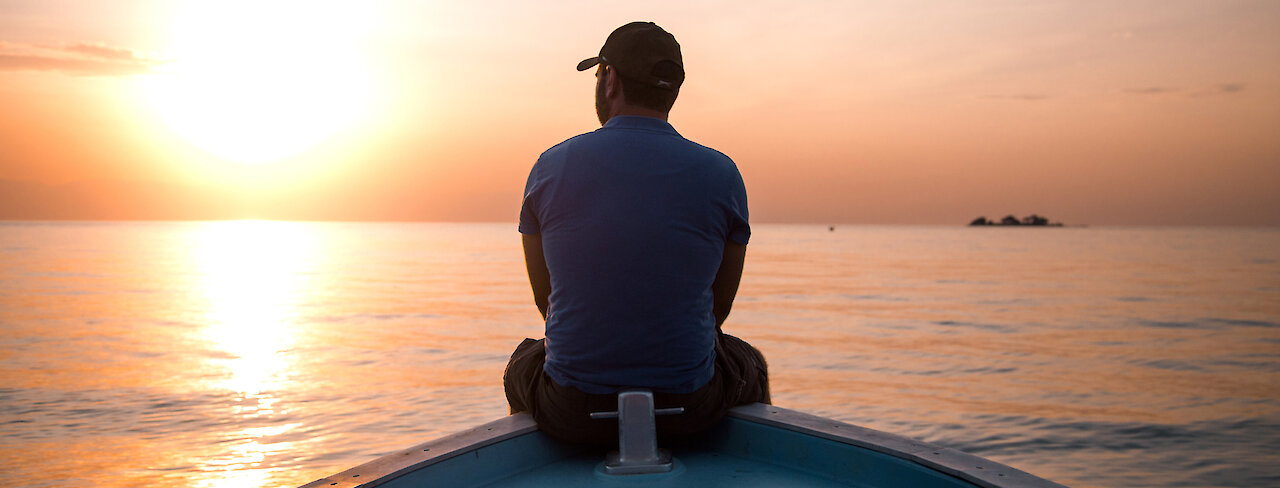Mann auf Boot mit Sonnenuntergang