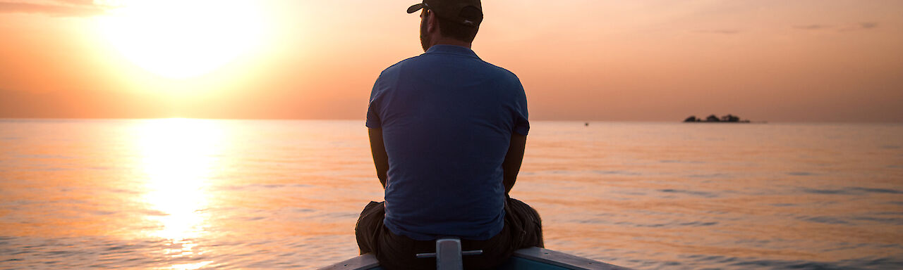 Mann auf Boot mit Sonnenuntergang
