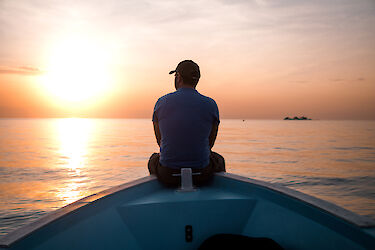 Mann auf Boot mit Sonnenuntergang