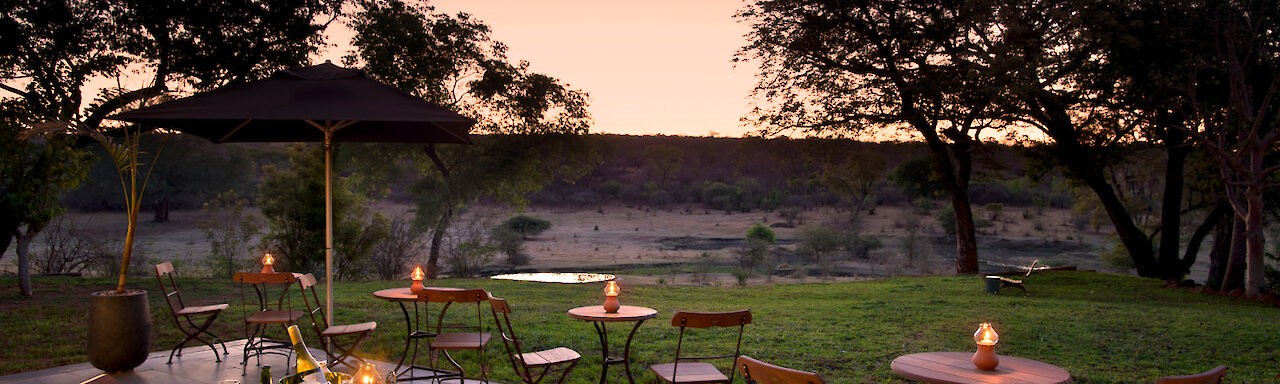 Stanley & Livingstone Boutique Hotel. Simbabwe - Terrasse mit Kerzenschein gedeckten Tischen und Blick auf Wasserloch