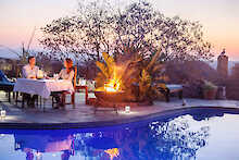 Ant´s Africa Safaris - Ant´s Nest, Pool mit Liegen und beleuchtetem Hauptgebäude im Hintergrund