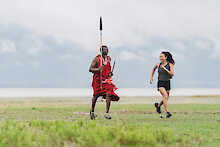 Frau joggt neben Massai