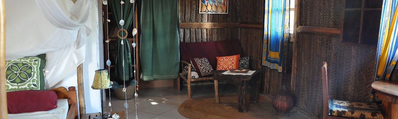 The Beach Crab Resort. Tansania. Blick ins Schlafzimmer mit Doppelbett, Schrank und Sitzgelegenheit.