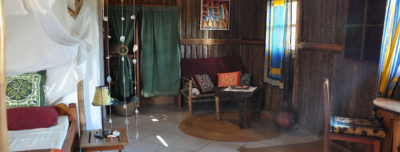 The Beach Crab Resort. Tansania. Blick ins Schlafzimmer mit Doppelbett, Schrank und Sitzgelegenheit.
