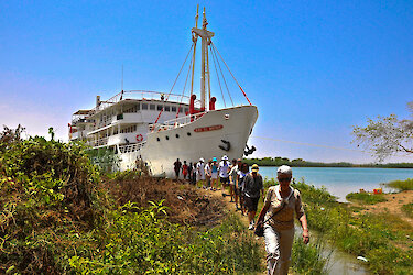 Senegalesin am Ufer des Senegalflusses mit dem Kreuzfahrtschiff Bou El Mogdad im Hintergrund