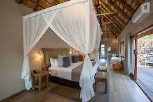 Arathusa Safari Lodge Unterkunft mit Doppelbett und Blick auf Terrasse mit Outdoor Dusche