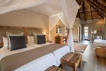 Arathusa Safari Lodge Unterkunft mit Doppelbett und Blick ins Bad mit Badewanne