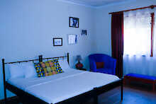 Carpe Diem Guest House Blick ins Zimmer auf Bett, Nachttisch und Sitzgelegenheit