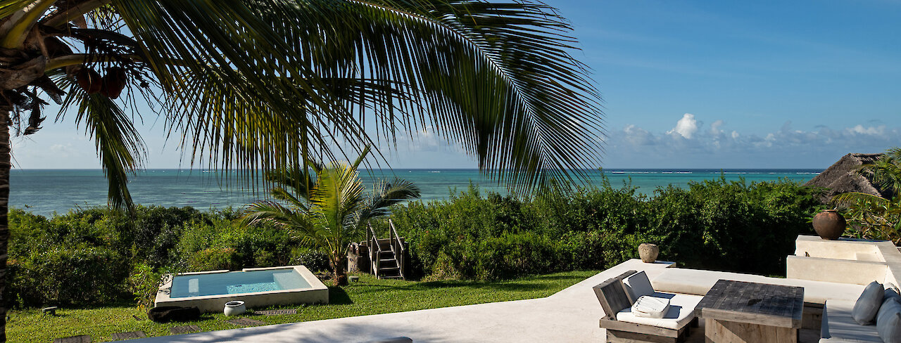 Qambani Luxury Resort mit Sitzmöglichkeit und Blick auf das Meer unter Palmen