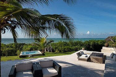 Qambani Luxury Resort mit Sitzmöglichkeit und Blick auf das Meer unter Palmen