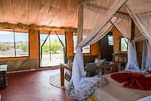 Africa Safari Lake Natron Camp Zeltinneres mit Doppelbett und Blick zur Terrasse