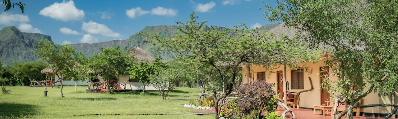 Eingang zu der Maasai Giraffe Eco Lodge mit grüner Wiese