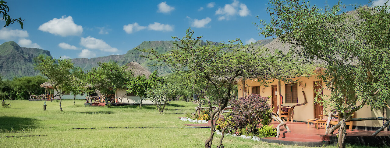 Eingang zu der Maasai Giraffe Eco Lodge mit grüner Wiese