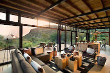 Marataba Mountain Lodge Lounge mit Sofas und Teelichtern mit großem Fenster und Blick zum Gebirge