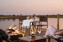 Abendessen im Außenbereich mit Feuerlager und Blick zum See der Xugana Island Lodge