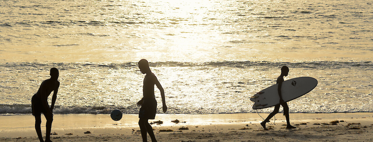 Kinder spielen am Strand Fußball beim Sonnenuntergang