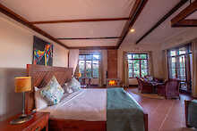 Ngorongoro Coffee Lodge Zimmer mit Doppelbett Feuer im Kamin und Sitzgelegenheiten