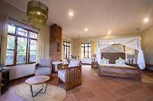 Ngorongoro Coffee Lodge Zimmer mit Doppelbett Kamin und Sitzgelegenheiten