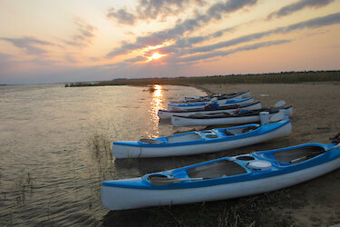 Kanus am Flussufer bei Sonnenuntergang
