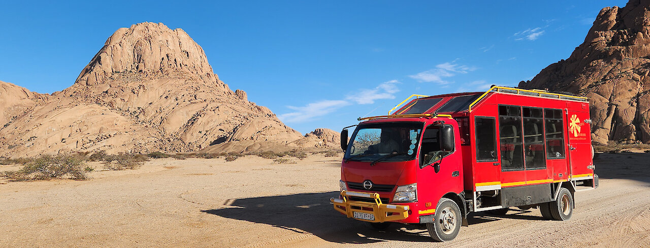 Roter Safari Truck in Wüstenlandschaft