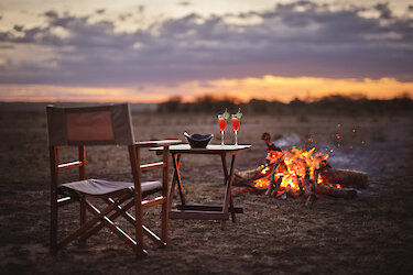 Ein Getränk bei Lagerfeuer und Sonnenuntergang im Tipilikwani Mara Camp