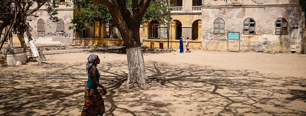 Bewohnerin läuft unter Bäumen lang auf Gorée