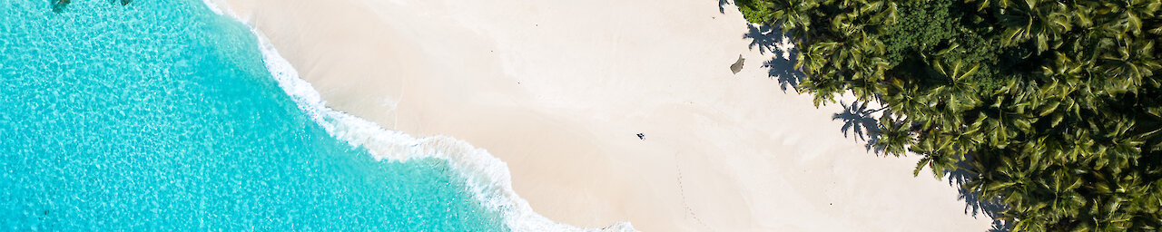Luftaufnahme von weißem Sandstrand und türkisem Wasser