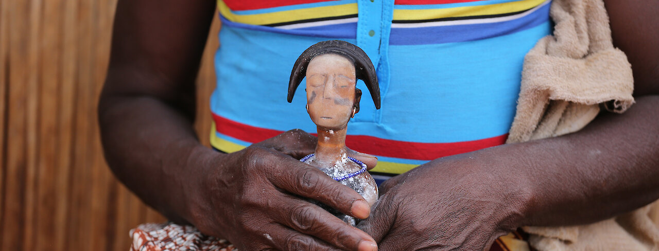 Eine Vodoo Zwillingspuppe auf dem Schoß einer Frau