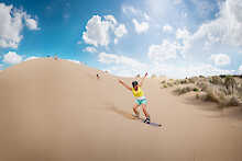 Eine freudige Frau beim Sandboarding