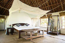 Großes Doppelbett mit Moskitonetz in der Emayani Beach Lodge