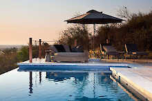 Poolbereich mit Ausblick und Liegen unter dem Sonnenschirm im Dolomite Camp