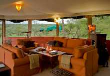 Lounge mit gemütlichen Sofas und grüner Umgebung im Kicheche Valley Camp